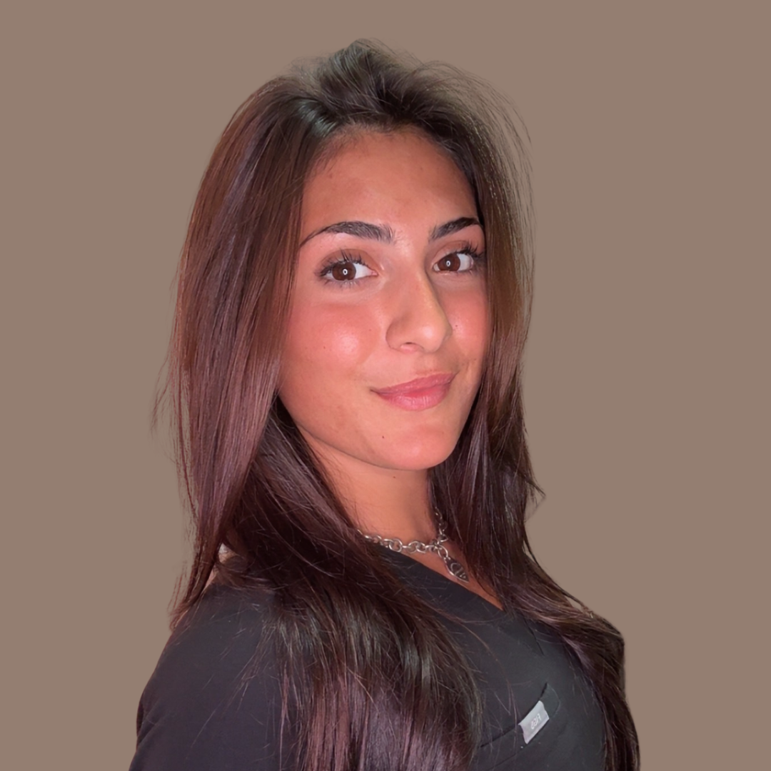 Portrait of a smiling woman with long dark hair wearing a black top and silver necklace, neutral brown background